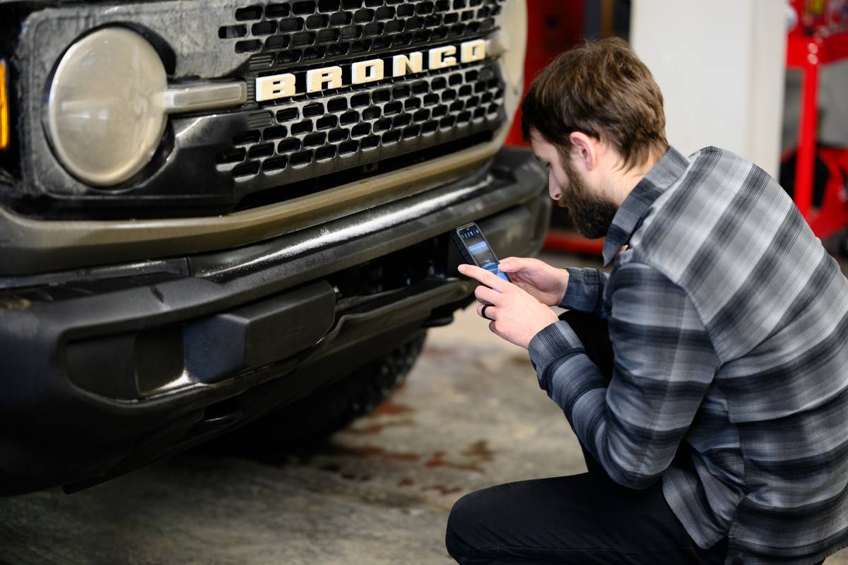 Technician documenting the front bumper of a Ford Bronco at Fix Auto Sherwood North