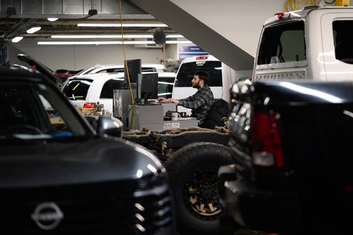Pickup truck chassis in the repair bay with a technician at a workstation at Fix Auto Sherwood North