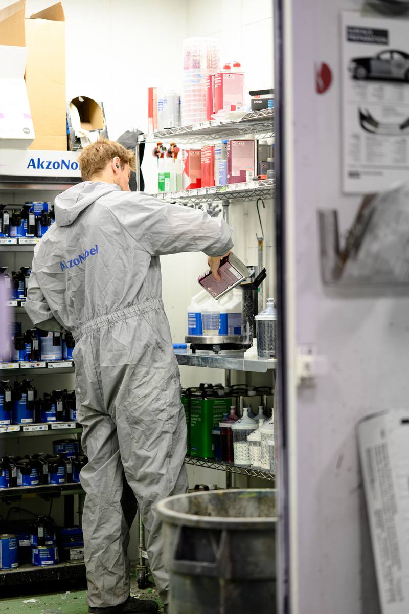 Painter in a paint suit working in the paint mixing room at Fix Auto Sherwood North